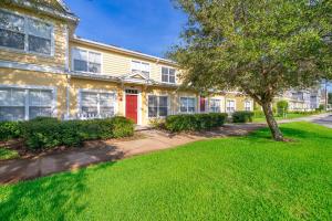 a yellow house with a red door and a tree at Enchanted Townhome near Disney Parks 3Br in Kissimmee