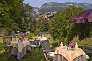 een groep tafels en stoelen met bloemen erop bij Angerburg Blumenhotel in Appiano sulla Strada del Vino