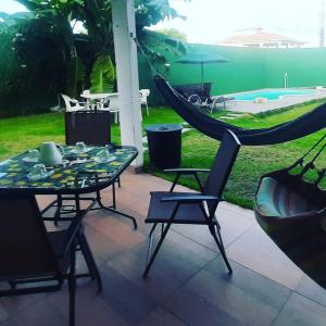 um pátio com uma rede de descanso, uma mesa e cadeiras em Casa pertinho da praia com piscina, wifi; em Vila Velha