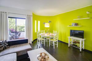 een woonkamer met gele muren en een tafel en stoelen bij Seaside Retreat with Pool, AC, and Fast Wi-Fi in Albufeira