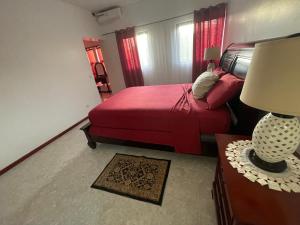 a bedroom with a red bed and a table with a lamp at Isa House - Private Rooms in a Shared Duplex in Praia