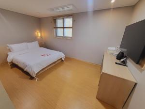 a bedroom with a bed and a desk with a television at Hotel razaB in Pohang