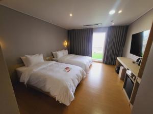 a hotel room with two beds and a flat screen tv at Hotel razaB in Pohang