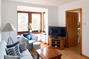a living room with a couch and a tv at Executive Apartment By Inverkeithing Train Station in Fife
