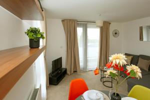ein Wohnzimmer mit einem Tisch und Stühlen sowie ein Wohnzimmer mit einem TV in der Unterkunft Autumn Heights Apartments in Telford