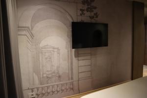 a drawing of a building on a wall with a television at Hani i Gjelit Hotel, Korce in Korçë