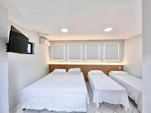 a room with two beds and a flat screen tv at POUSADA BEIRA MAR in Fortaleza