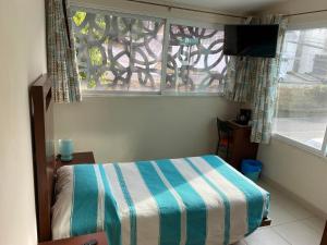 普埃布拉的住宿－CORDIALITY INN，一间卧室设有一张床和一个带电视的窗户。
