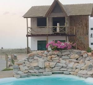 una casa con una pared de piedra y una casa con flores rosas en Chaleville 2301, Praia do maramar, luis correia en Luis Correia