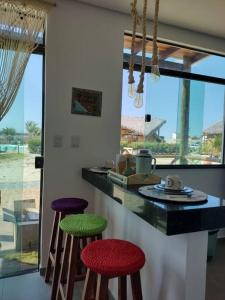 a kitchen with colorful stools in front of a counter at Chaleville 2301, Praia do maramar, luis correia in Luis Correia