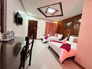 a hotel room with three beds and a television at Mariafe Inn in Puerto Princesa City