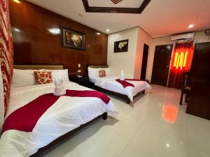 a bedroom with two beds with red and white sheets at Mariafe Inn in Puerto Princesa City
