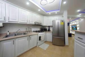 a kitchen with white cabinets and a stainless steel refrigerator at MODERN 3 BDRM KING BED 2BATHRM HOT WATER WIFI in Santo Domingo