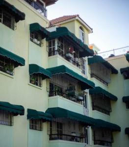 a building with balconies with green umbrellas at MODERN 3 BDRM KING BED 2BATHRM HOT WATER WIFI in Santo Domingo