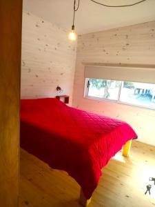 Cama roja en habitación de madera con ventana en Nio de Baixo, en La Pedrera