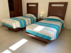 two beds in a hotel room with sunlight shining on them at CORDIALITY INN in Puebla