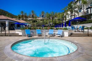 a small pool with blue chairs and umbrellas at 2br Condo - Sleeps 6 - Garage - Wifi Laguna in Laguna Niguel