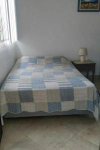 a bed in a bedroom with a blue and white quilt at Casa vacacional en Pedro Vicente Maldonado in Pedro Vicente Maldonado