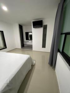 a bedroom with a white bed and a television at Tokyo Motel in San Bernabé Amaxac de Guerrero