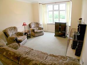 a living room with a couch and two chairs and a window at Tyn Y Graig Cottage in Crynant