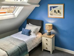 a bedroom with blue walls and a bed with a night stand at 8 Old School Mews in Shanklin