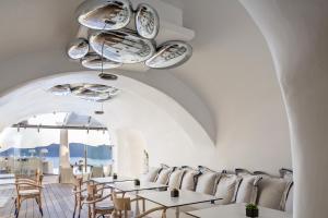 a restaurant with white walls and tables and chairs at Katikies Kirini Santorini - The Leading Hotels Of The World in Oia