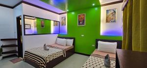 a room with two beds and a green wall at Mina Grande Beach Cottages in El Nido
