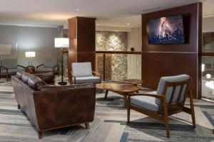 a lobby with a couch and chairs and a tv at Four Points by Sheraton Victoria Gateway in Victoria