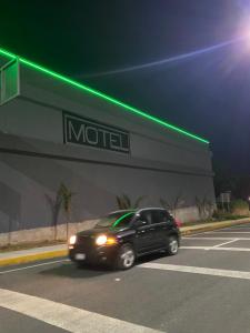 a black suv driving past a moco building at night at Tokyo Motel in San Bernabé Amaxac de Guerrero