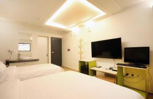 a hotel room with two beds and a flat screen tv at Bandal Hotel in Busan