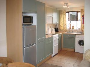 a kitchen with green cabinets and a refrigerator at The Granary in Burscough