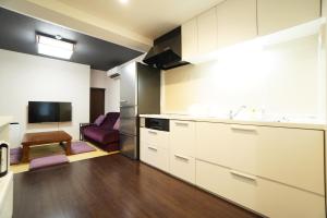 a kitchen with white cabinets and a living room at ANGO KYOTO Ⅰ in Kyoto