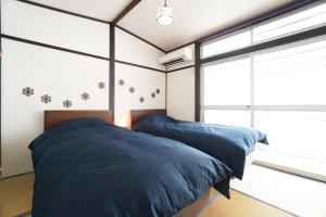 two beds in a bedroom with large windows at ANGO KYOTO Ⅰ in Kyoto