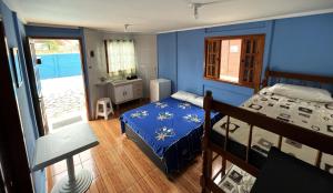 - une chambre bleue avec un lit et un balcon dans l'établissement Chalé Master Caraguatatuba cond Alto Padrão Massaguaçu, à Caraguatatuba