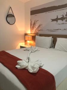 una camera d'albergo con un letto e un asciugamano sopra di Apê Laranja Iloa Barra de São Miguel a Barra de São Miguel