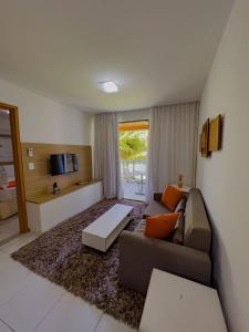 a living room with a couch and a table at Apê Laranja Iloa Barra de São Miguel in Barra de São Miguel