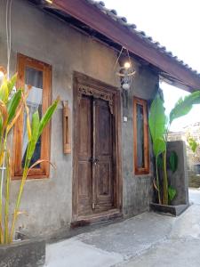 een klein huis met een houten deur erop bij Classic Local House Grenceng in Denpasar