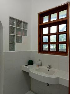 a white bathroom with a sink and a window at Larot's Vacation House - Rooms Only in Siquijor