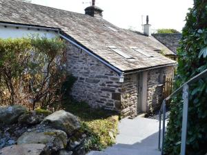 an old stone house with a stone pathway leading to it at Scot Beck Cottage in Troutbeck