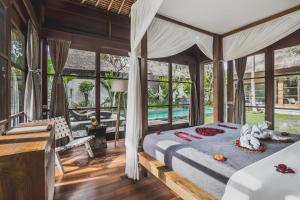 a bedroom in a villa with a bed and a desk at Luwak Estate in Ubud