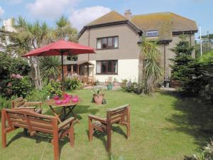 a garden with a table and chairs and a red umbrella at The Gazebo in Marazion