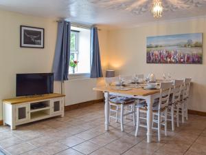 a dining room with a table and a tv at Penrhiw Meredith in Llanfynydd