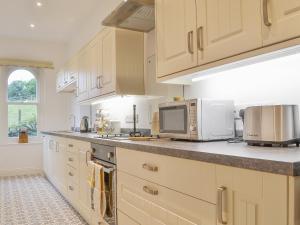 uma cozinha com armários brancos e um micro-ondas em 1 School Cottage em Troutbeck Bridge