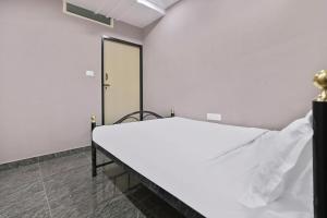a white bed in a room with a door at SPOT ON Krishnaa Comforts Near Cubbon Park in Bangalore