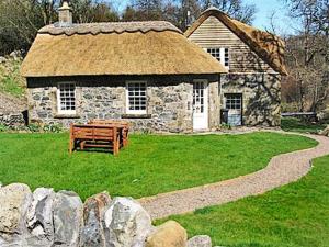a stone building with a bench in front of it at Forget Me Not - Skkz in Dalmellington