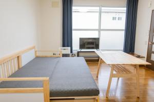 una camera da letto con un letto, un tavolo e una finestra di Furano Zone Ski Condo 202喫煙可103禁煙 a Furano