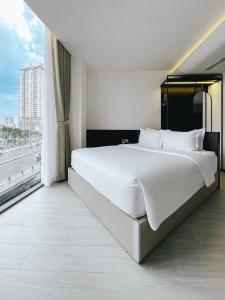 uma grande cama branca num quarto com uma janela em The Concept Hotel HCMC- District 1 em Ho Chi Minh