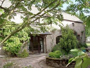 een stenen huis met een deur in een tuin bij The Stables Trap Farm in Wolves Newton