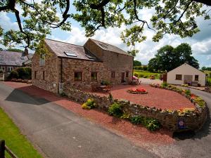 a stone building with a flower garden in front of it at New Park Farm - Church Cottage in Ireby