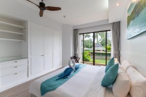 Allamanda Laguna Phuket في شاطئ بانغ تاو: غرفة نوم بيضاء مع سرير كبير ونافذة